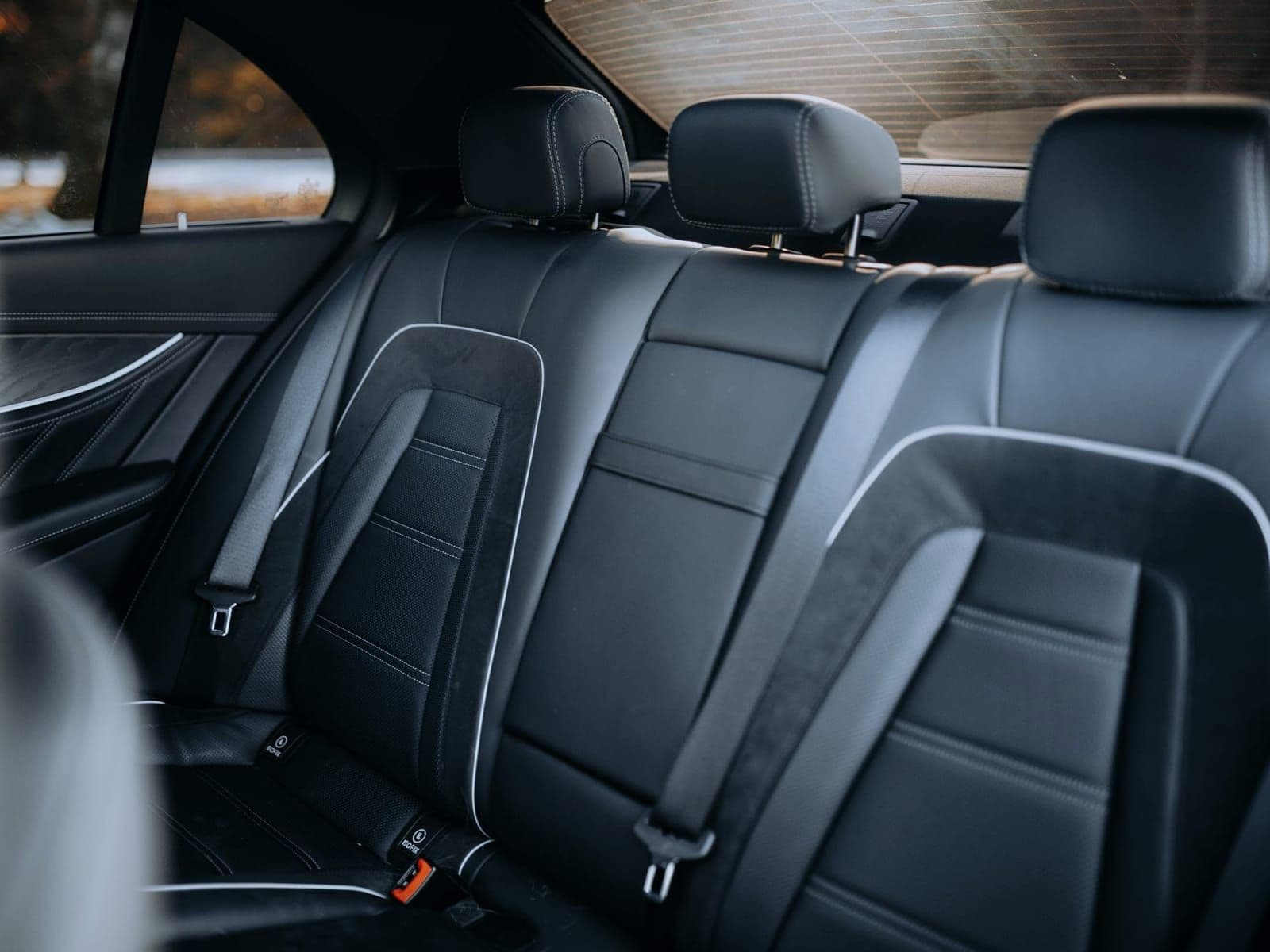Black leather rear bench seat of a luxury sedan with visible stitching detail