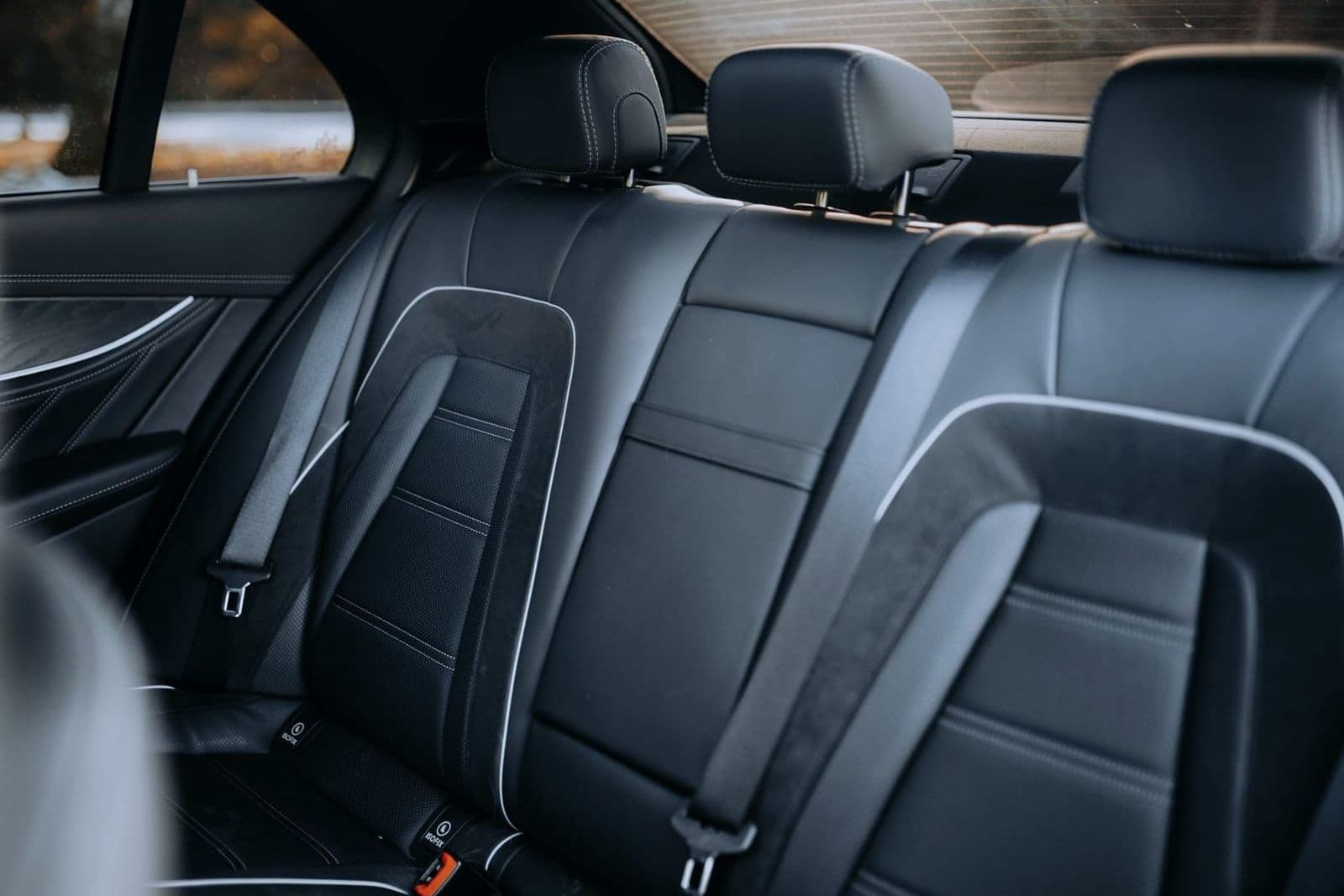 Black leather rear bench seat of a luxury sedan with visible stitching detail